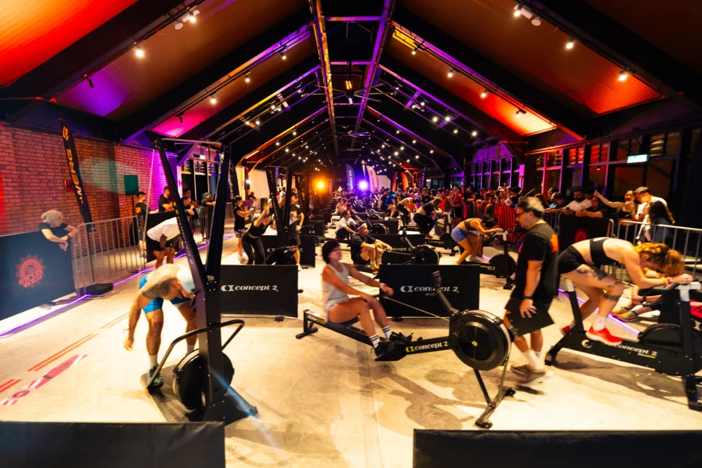 Indoor fitness competition arena with rowing machines stationary bikes and ambient lighting